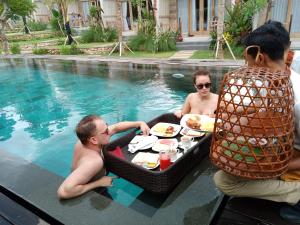 a group of people sitting around a table in a swimming pool at Kompyang Cottage in Nusa Penida