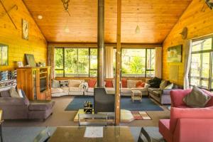 una sala de estar con sofás, mesas y ventanas en JunoHall Backpackers, en Waitomo Caves