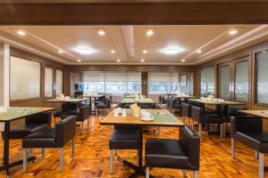 a dining room with tables and chairs and windows at Tropicana Suites in Manila