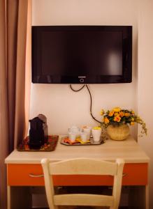 a table with a tv on a wall with cups and flowers at Sweet Rooms Cagliari in Cagliari
