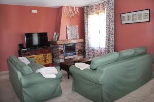 salon z 2 zielonymi kanapami i kominkiem w obiekcie Casa Rural El Olivar de Valdefuentes w mieście Valdefuentes