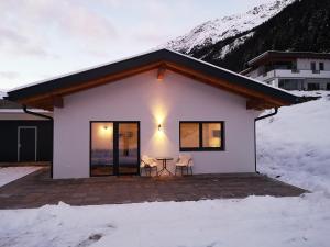 Une petite maison blanche avec une table dans la neige dans l'établissement Alpenchalet Pitztal, à Sankt Leonhard im Pitztal