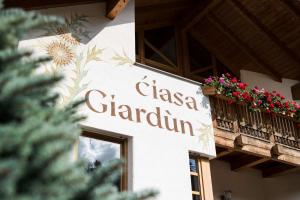 a sign on the side of a building with flowers on a balcony at Residence Ciasa Giardun in La Villa