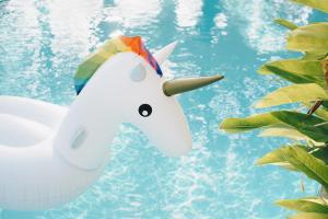 a white unicorn toy next to a swimming pool at The Pineapple Hotel in Krabi town +76 photos