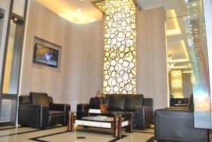 una sala de espera con sillas de cuero negro y una mesa en Hotel Harmony In & Karaoke en Pontianak