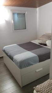 uma cama num quarto branco com uma janela em Almasol em Cassano delle Murge