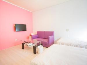 a living room with a purple couch and a bed at Hotel Palm Tree Hill in Okinawa City