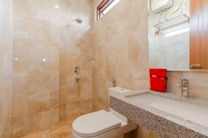 un bagno con un water, un lavandino e uno specchio di RedDoorz Plus @ CBD Bintaro a Peladen Altre 37 foto