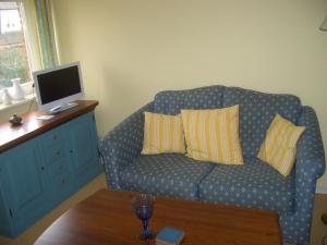 uma sala de estar com um sofá azul com almofadas em Reethof em Tinnum