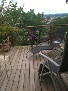 una terraza de madera con sillas y un jarrón de flores en Appart d'Hôtes Brive, en Brive-la-Gaillarde