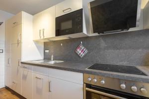 a kitchen with white cabinets and a sink and a microwave at Wohnung "AlpppTraum" mit Traumblick in Oberstdorf +1 photo