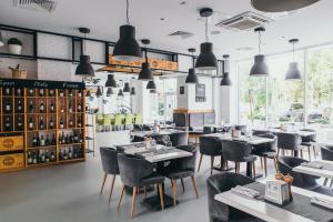 un restaurante con sillas negras, mesas y ventanas en Hotel Rakurs, en Ulyanovsk