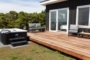 una terraza de madera con bañera de hidromasaje en una casa en Skylark Lodge, en Okaihau