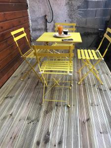 een gele tafel en stoelen op een houten vloer bij Chambre2 Résidence Beauregard in Koungou