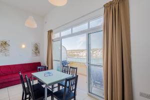 a living room with a red couch and a table with chairs at Blue Harbour Seafront 3 bedroom apartment, with spectacular sea views from terrace - by Getawaysmalta in St. Paul's Bay