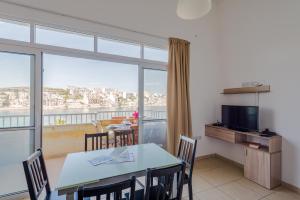 a dining room with a table and a large window at Blue Harbour Seafront 3 bedroom apartment, with spectacular sea views from terrace - by Getawaysmalta in St Paul's Bay