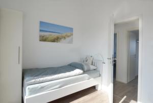 a white bedroom with a bed and a painting on the wall at Wilbur in Olpenitz