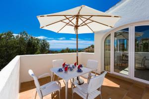 una mesa blanca y sillas con sombrilla en el balcón en Villas Guzman - Milou, en Benissa