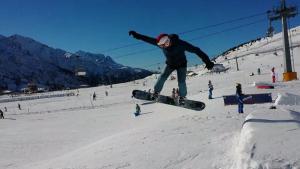 Eine Person, die einen Trick auf einem Snowboard in der Luft macht. in der Unterkunft Monolocale a Passo Tonale in Passo del Tonale