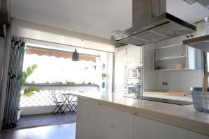 cocina con armarios blancos y ventana grande en Apartamento Playa Cabanyal, en Valencia