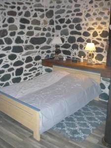 uma cama num quarto com uma parede de pedra em lecurieabedous em Bedous