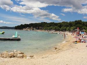 a beach with a lot of people in the water at Apartments Domino in Pakoštane