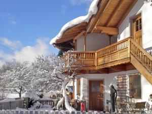ein Haus mit einer Holzterrasse im Schnee in der Unterkunft Ferienwohnung Hofmann in Kiefersfelden
