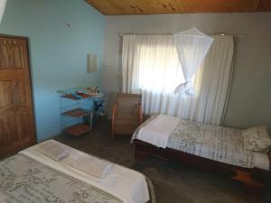 a bedroom with two beds and a window with a desk at Gateway Guest House in Monkey Bay
