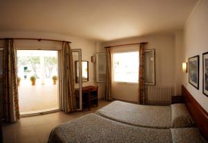 a bedroom with a bed and a large window at Apartamentos Villa Sirena in Cala Figuera +17 photos