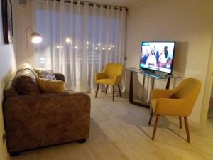 a living room with a couch and chairs and a television at Departamento frente al mar in La Serena +11 photos