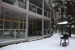 a house in the snow with a chair and an umbrella at Baza otdiha Lesnaya Obitel in Roshchino