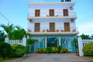 ein weißes Gebäude mit orangefarbenen Fenstern und einem Balkon in der Unterkunft Hotel Kiyara in Dambulla