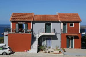 een rood-wit huis met een auto voor de deur bij Greg's apartment in Argostoli
