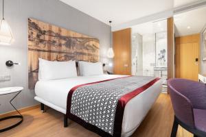 ポルトにあるユーロスターズ ポルト セントロの大きなベッドと紫色の椅子が備わるホテルルームです。