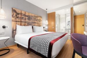 a hotel room with a large bed and a purple chair at Eurostars Porto Centro in Porto