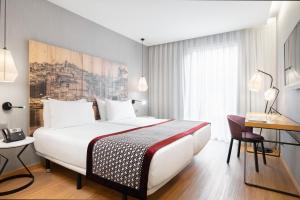 a hotel room with a large bed and a desk at Eurostars Porto Centro in Porto