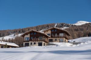 a large house in the snow in front of a mountain at Chalet Bello in Livigno