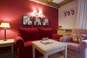 a living room with a red couch and two chairs at Das Georg Boutique-Hotel in Lech am Arlberg