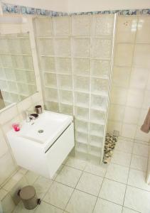 y baño blanco con lavabo y ducha. en Gîte Hibiscus Destrellan, en Baie-Mahault
