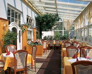 ein Restaurant mit Tischen und Stühlen in einem Gebäude in der Unterkunft Hotel - Restaurant Kurhaus Klotzsche in Dresden