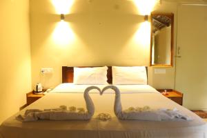 a bed with two swans making a heart on it at Sea Shades Palolem Resort in Palolem