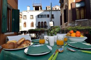 un tavolo con una tovaglia verde con pane e succo d'arancia di Charming Venice Apartments  a Venezia