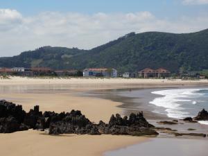 a beach with rocks in the sand and houses at Hotel Los Juncos in Noja