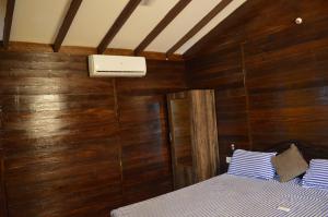 a bedroom with wooden walls and a bed with blue and white pillows at Royal Touch Beach Huts in Palolem