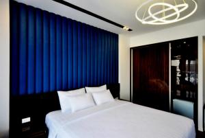 una camera da letto con un grande letto bianco con tende blu di Royal Dragon Boutique Hotel ad Ho Chi Minh
