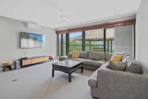 a living room with a couch and a tv at Mandalay Luxury Retreat in Airlie Beach