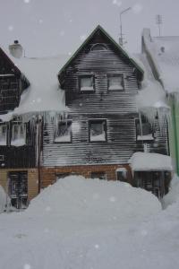a house covered in snow with a pile of snow at Boží Dar 96 in Boží Dar