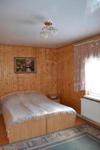 Schlafzimmer mit einem Bett mit Holzwänden und einem Fenster in der Unterkunft Карпатський Дуб in Jaremtsche