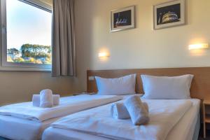 two beds in a hotel room with white sheets and pillows at Familienhotel Citylight in Berlin