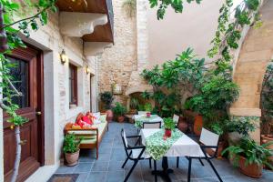 patio ze stołami, krzesłami i roślinami w obiekcie Casa Moazzo Suites and Apartments w Retimnie